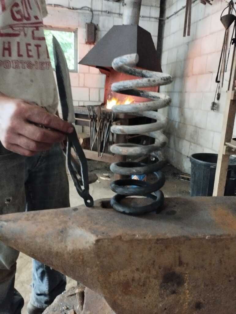un ressort à côté d'un couteau. Le couteau a été forgé à partir du ressort